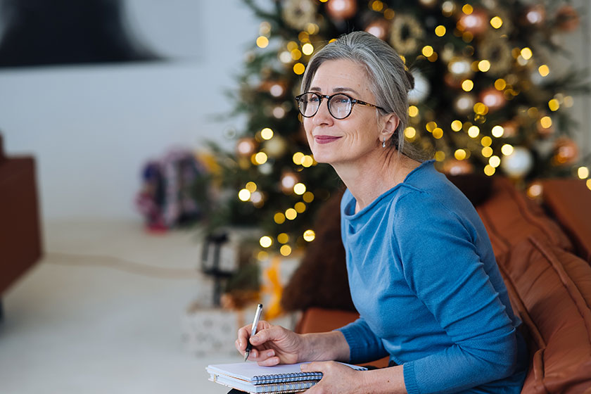 Happy senior woman in glasses thinking and write in a diary