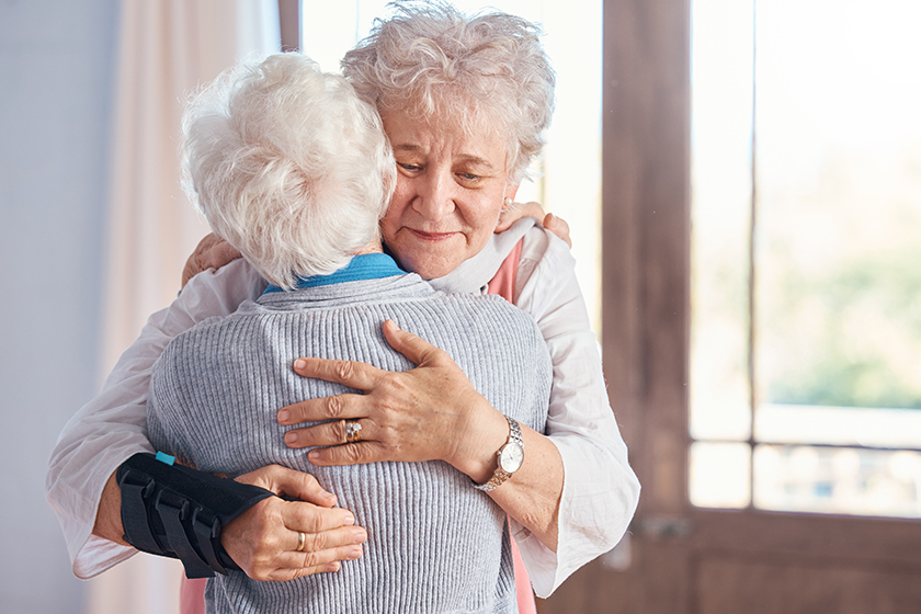 Elderly women, hug and nursing home, friends and support, comfort and care, together with bond. Senior people hugging, retirement and love with friendship in retirement home and connection