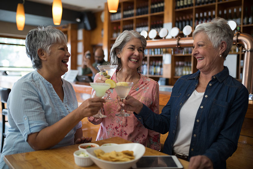 Senior female friends toasting glass of cocktail