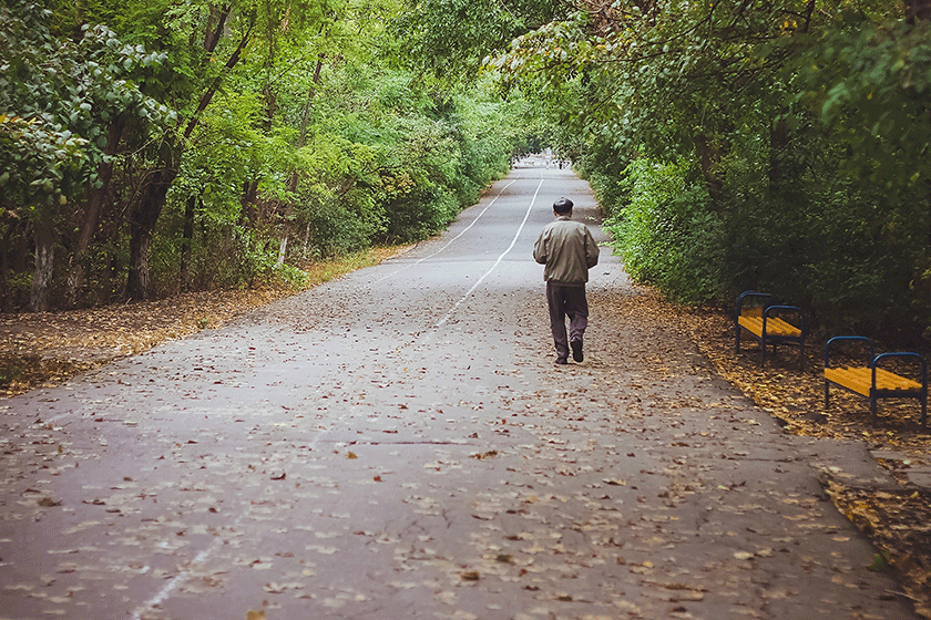 An elderly man is walking trough the park